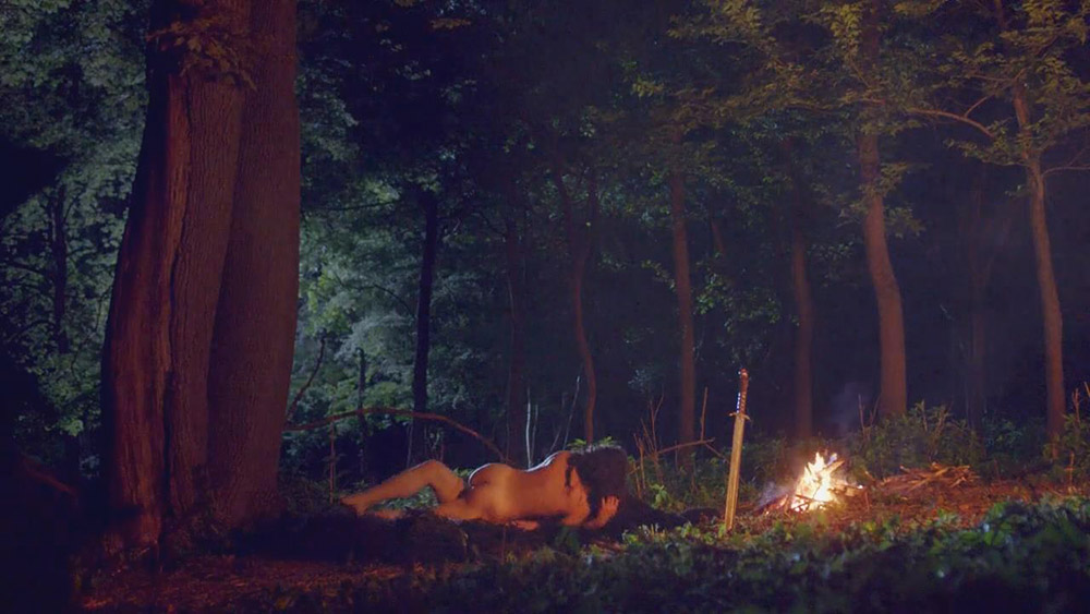 Sexy Charlie Murphy nude is standing in the woods with a guy. 